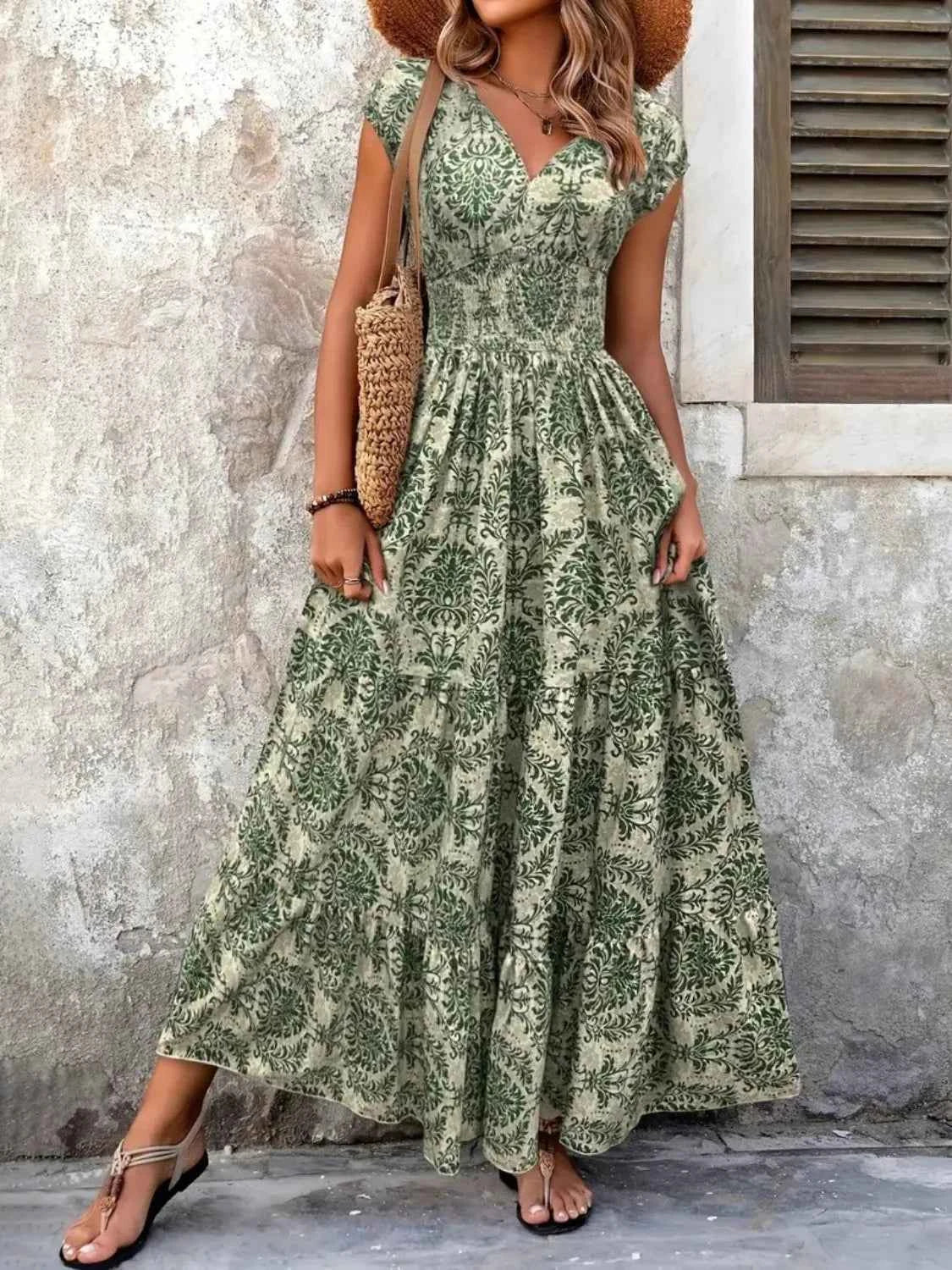 Woman wearing a green floral dress against a textured wall.