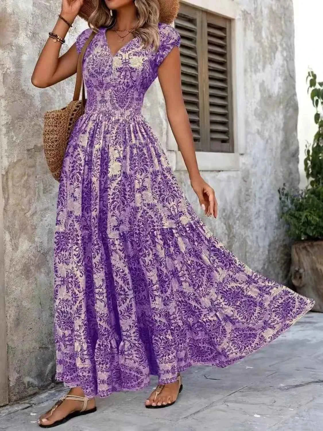 Woman wearing a purple floral dress standing against a stone wall.