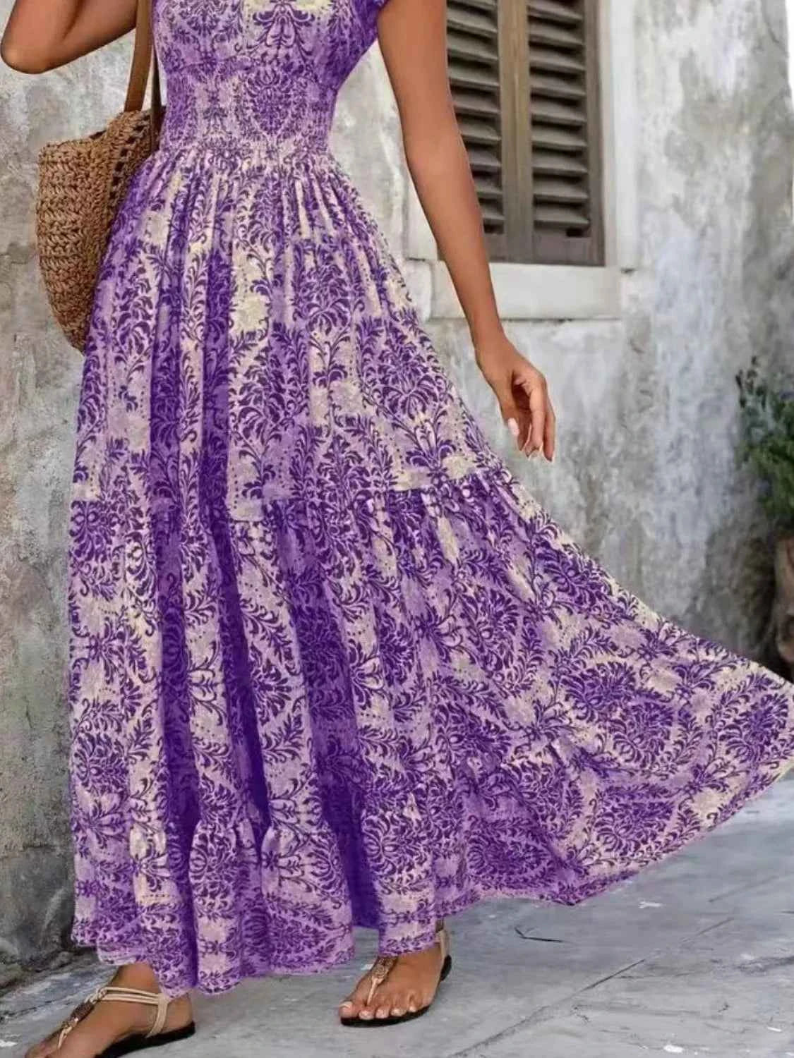 Person wearing a purple floral dress standing against a stone wall.